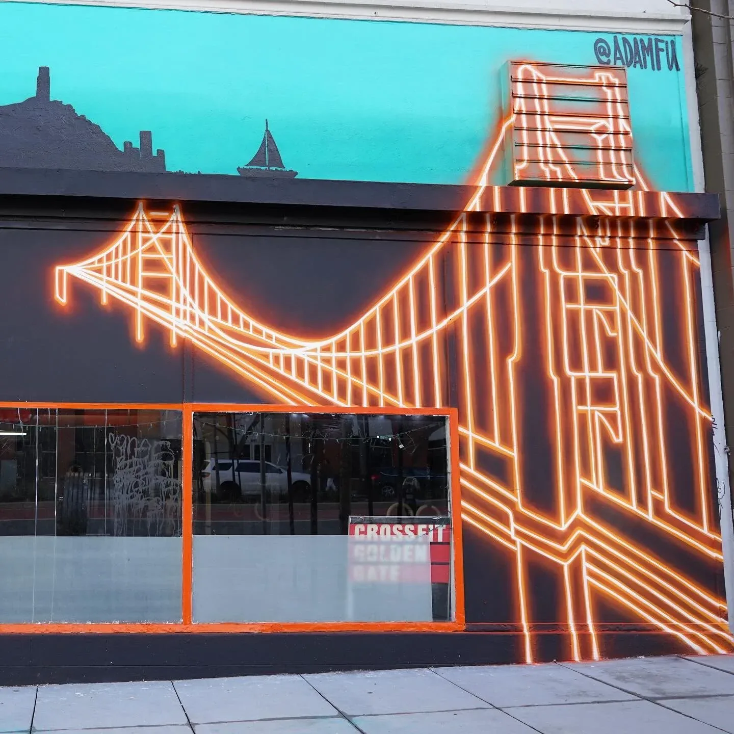 Large-scale exterior mural of the Golden Gate Bridge rendered in glowing orange neon lines on dark grey wall