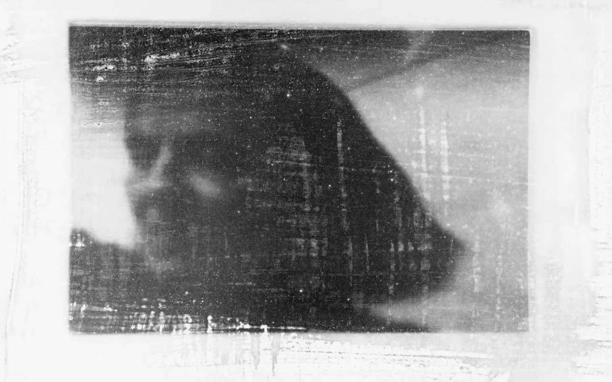 Abstract black and white photographic or print work showing a ghostly silhouetted head overlaid with architectural grid textures