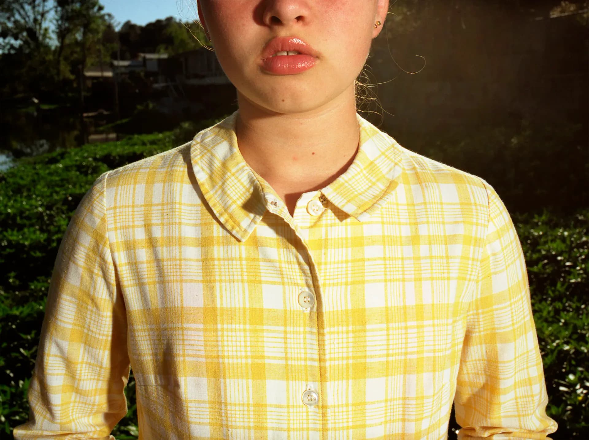 Close-up portrait of young woman in yellow plaid shirt outdoors