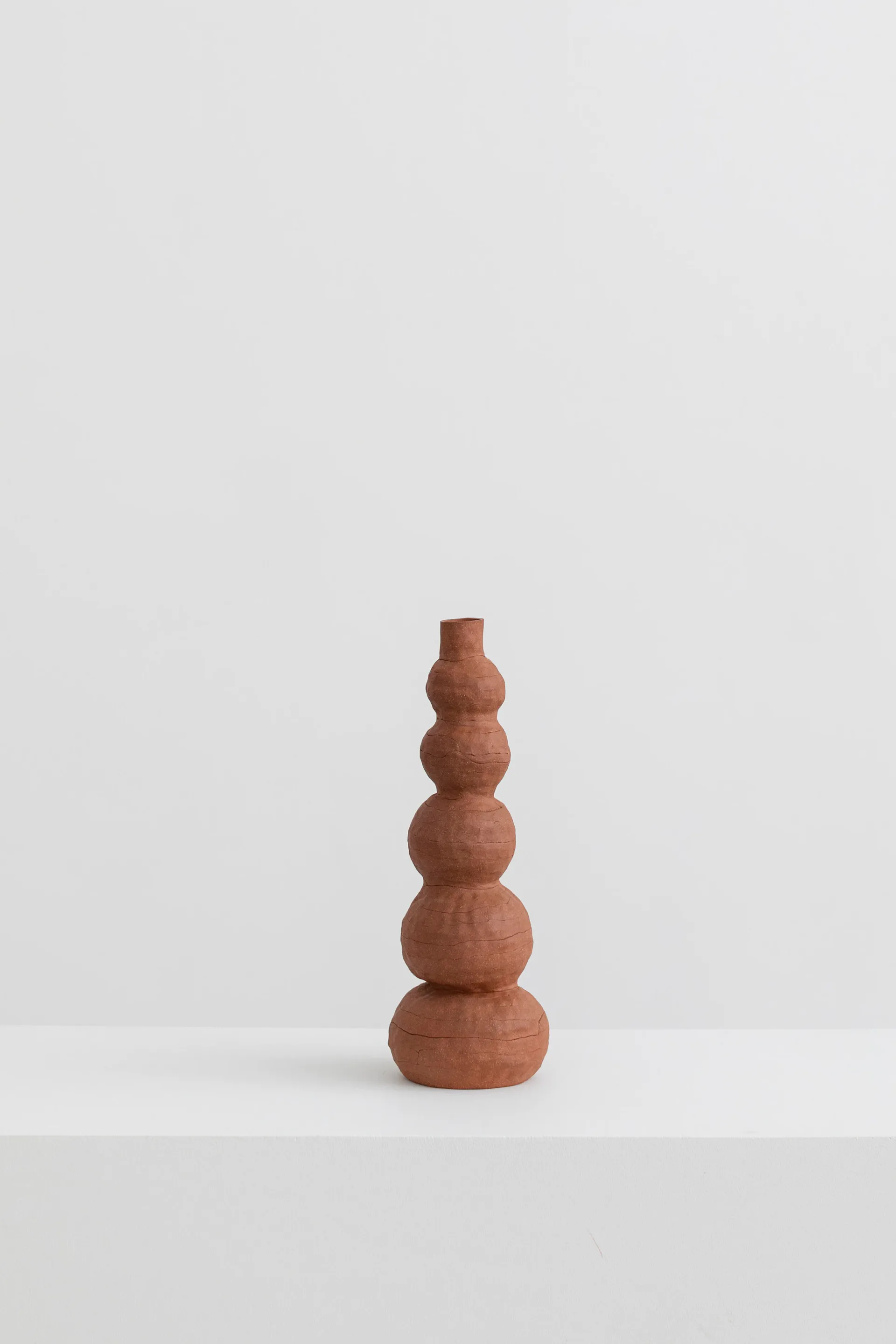 Collection of terracotta ceramic vessels of varying forms arranged on studio floor