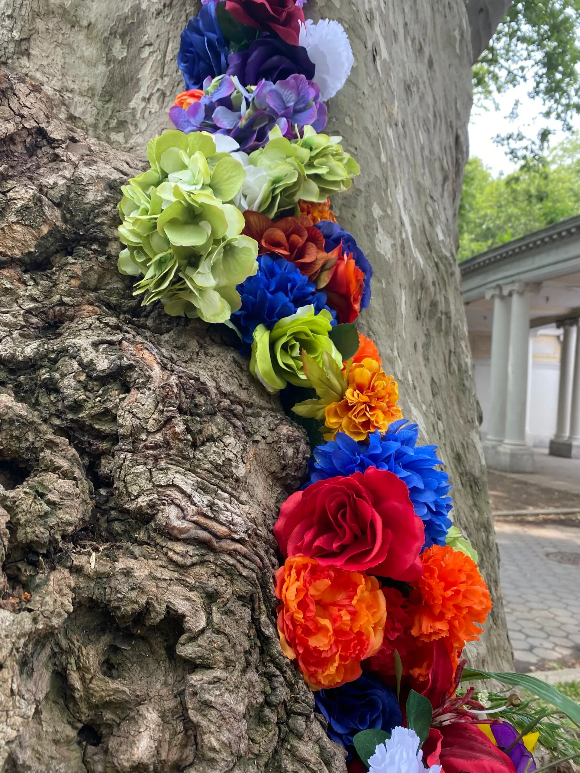 Close-up of colorful artificial flowers arranged along a tree trunk crevice