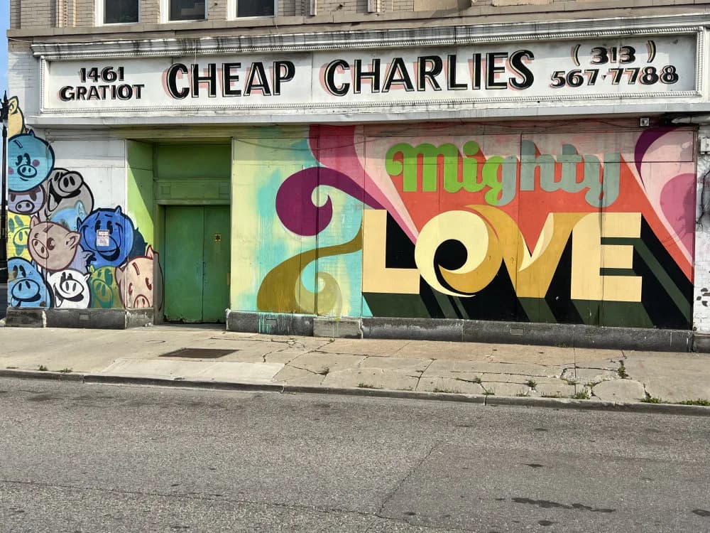 Storefront mural with "LOVE" text in black, yellow, and multicolored swirling abstract shapes in pink, green, and gold tones.