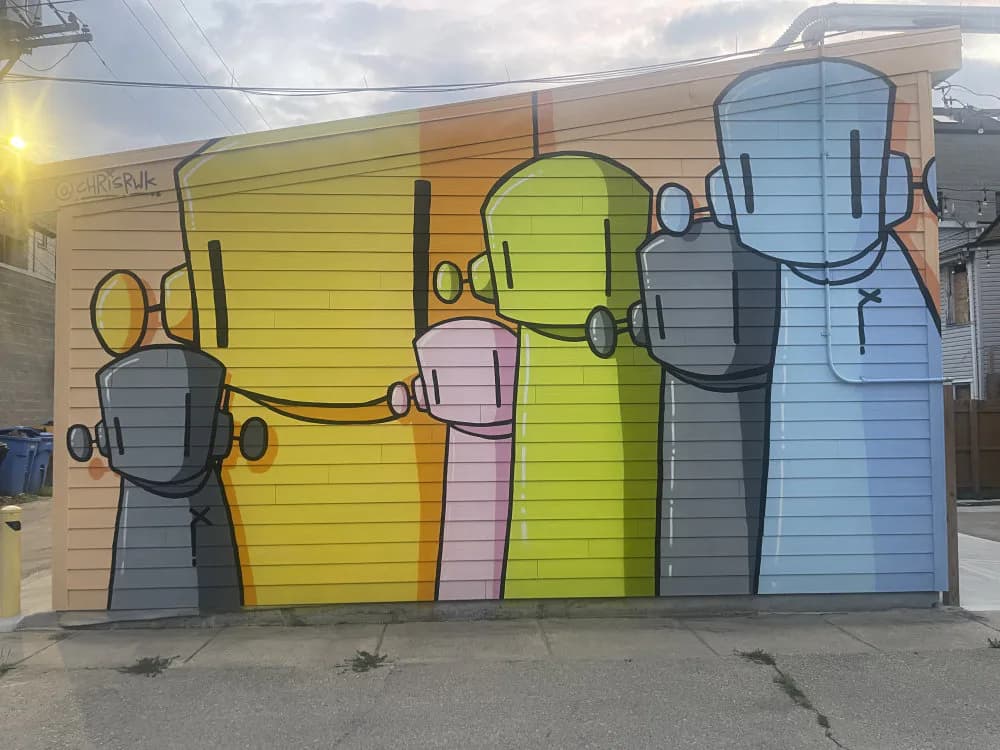 Mural featuring six colorful robot figures in yellow, green, pink, blue, and gray on a wooden garage door, with headphones and outstretched arms.