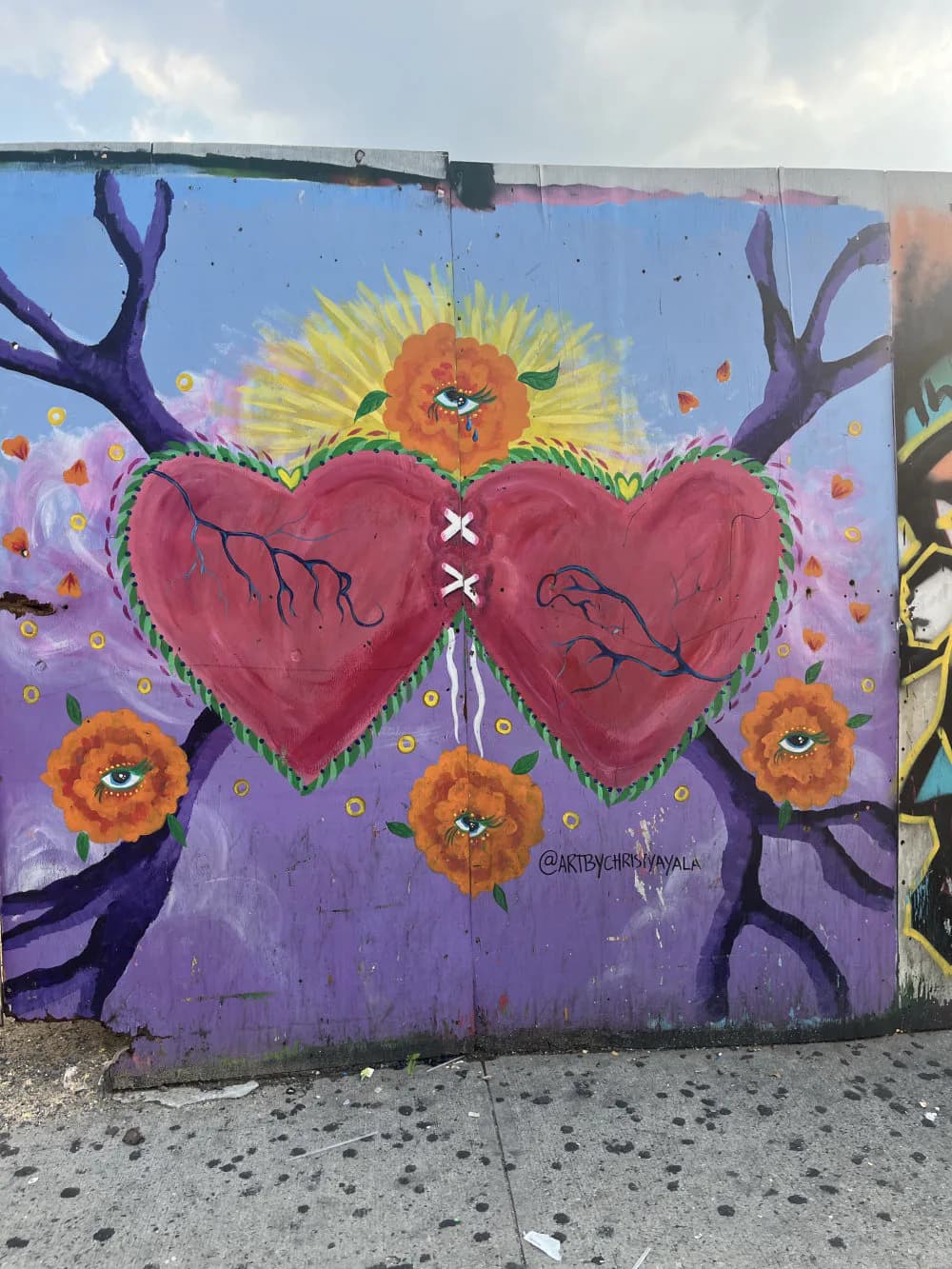 Mural featuring two red hearts with branch designs, purple tree limbs, yellow and orange sunflowers, and falling petals on a blue-purple gradient background.