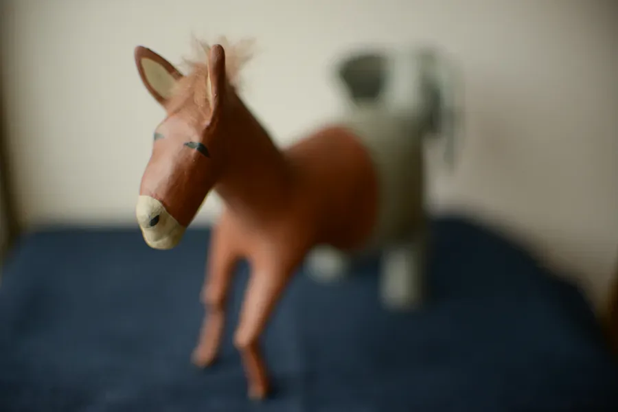 Small brown horse sculpture figurine on dark surface, minimalist style with subtle details.