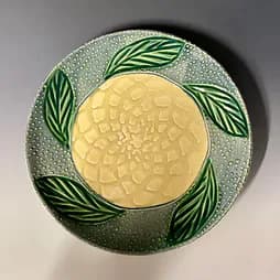 Ceramic plate with yellow flower and green leaf motif