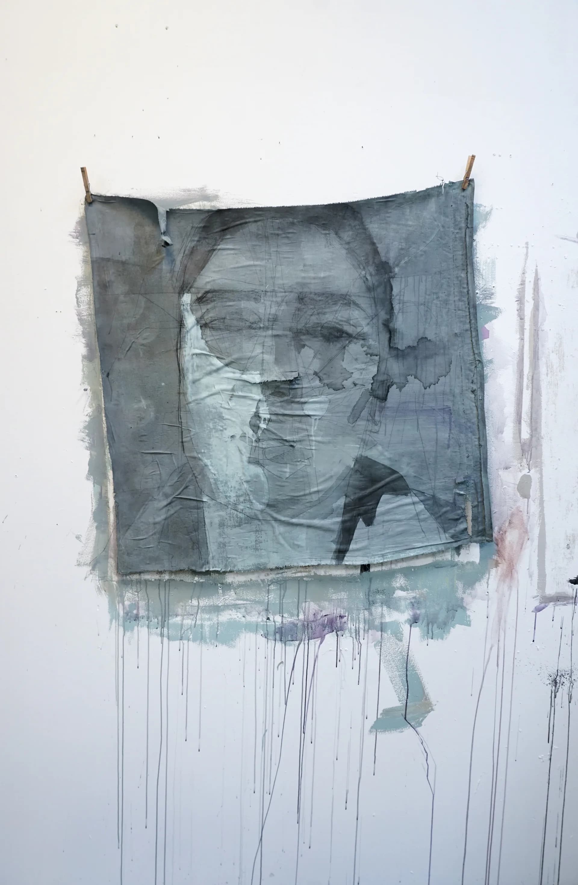 Large fabric portrait pinned to wall with clothespins, figure with braided hair rendered in ink and pencil on fabric