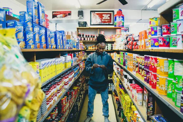 Person walking through colorful grocery store aisles lined with packaged products and bright signage.