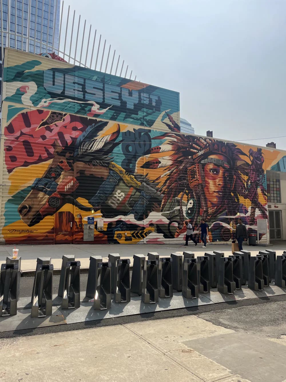 Large-scale mural by Dragon76 featuring stylized animals and vibrant colors in teal, red, yellow, and orange on building exterior.