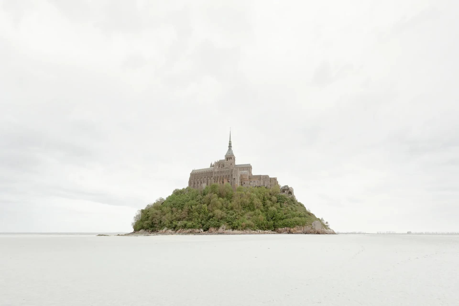 Mont Saint-Michel isolated on flat tidal flats under overcast sky