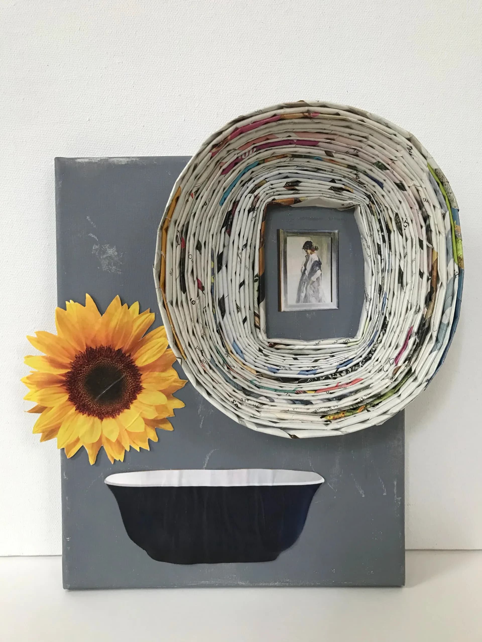 Mixed media assemblage with woven paper bowl, sunflower collage, and small framed figure on painted canvas