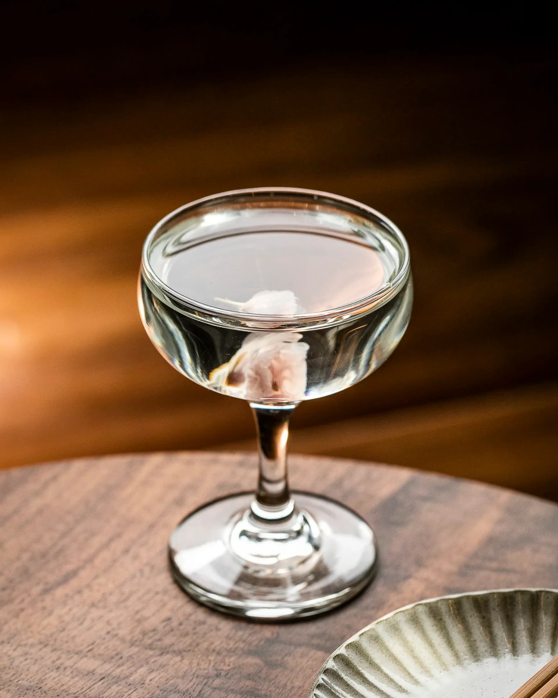 Two grapefruit honey cocktails in ribbed coupe glasses with citrus and honey props against warm terracotta wall