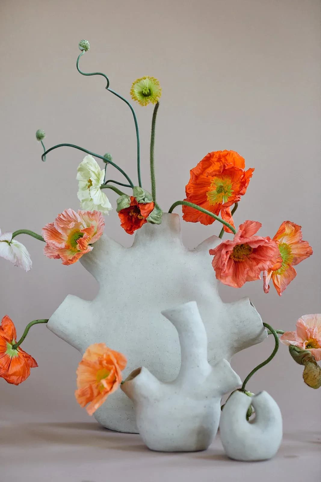 Sculptural white ceramic vase with poppy flowers in orange and pink
