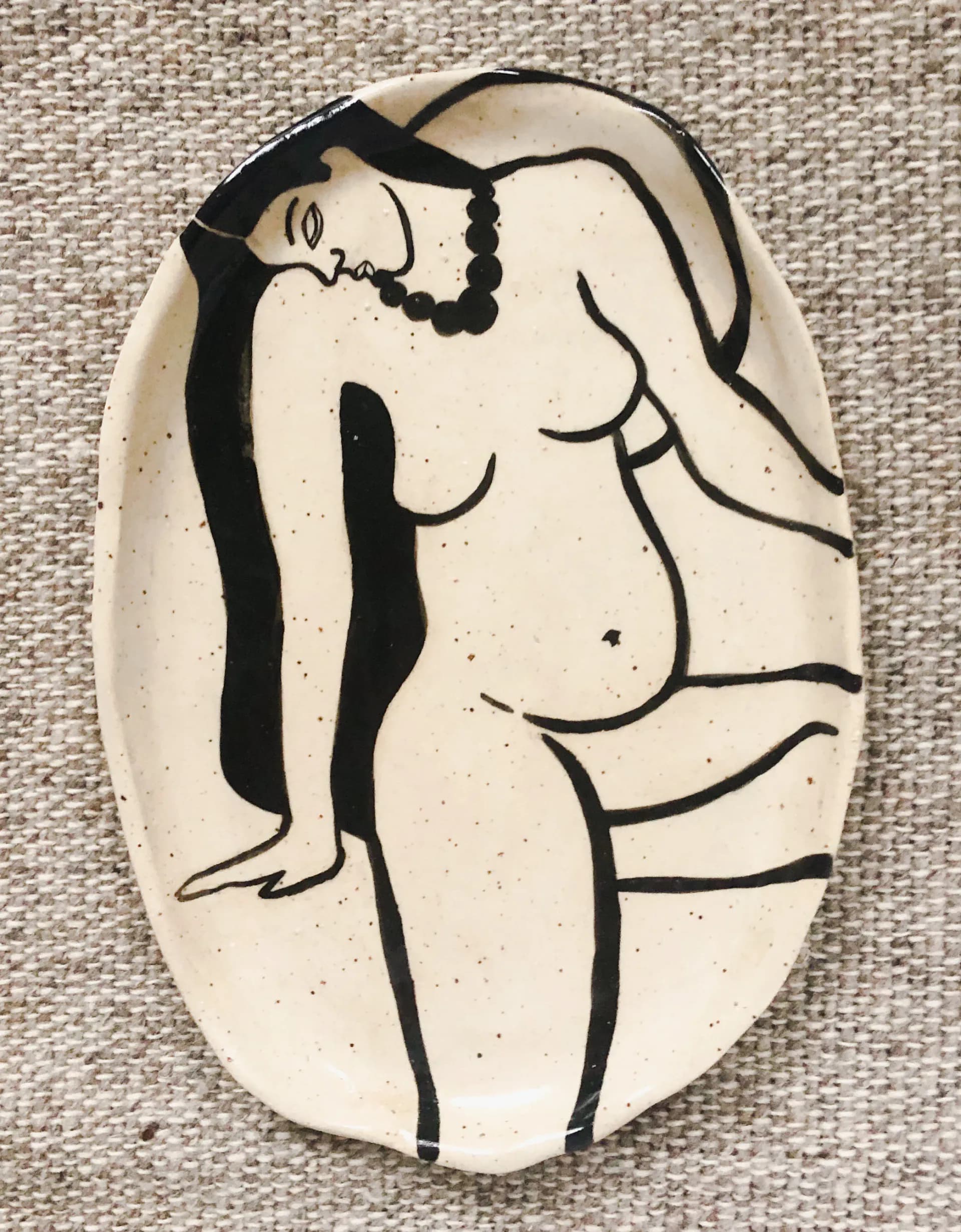 Oval ceramic plate with hand-painted nude female figure wearing a necklace