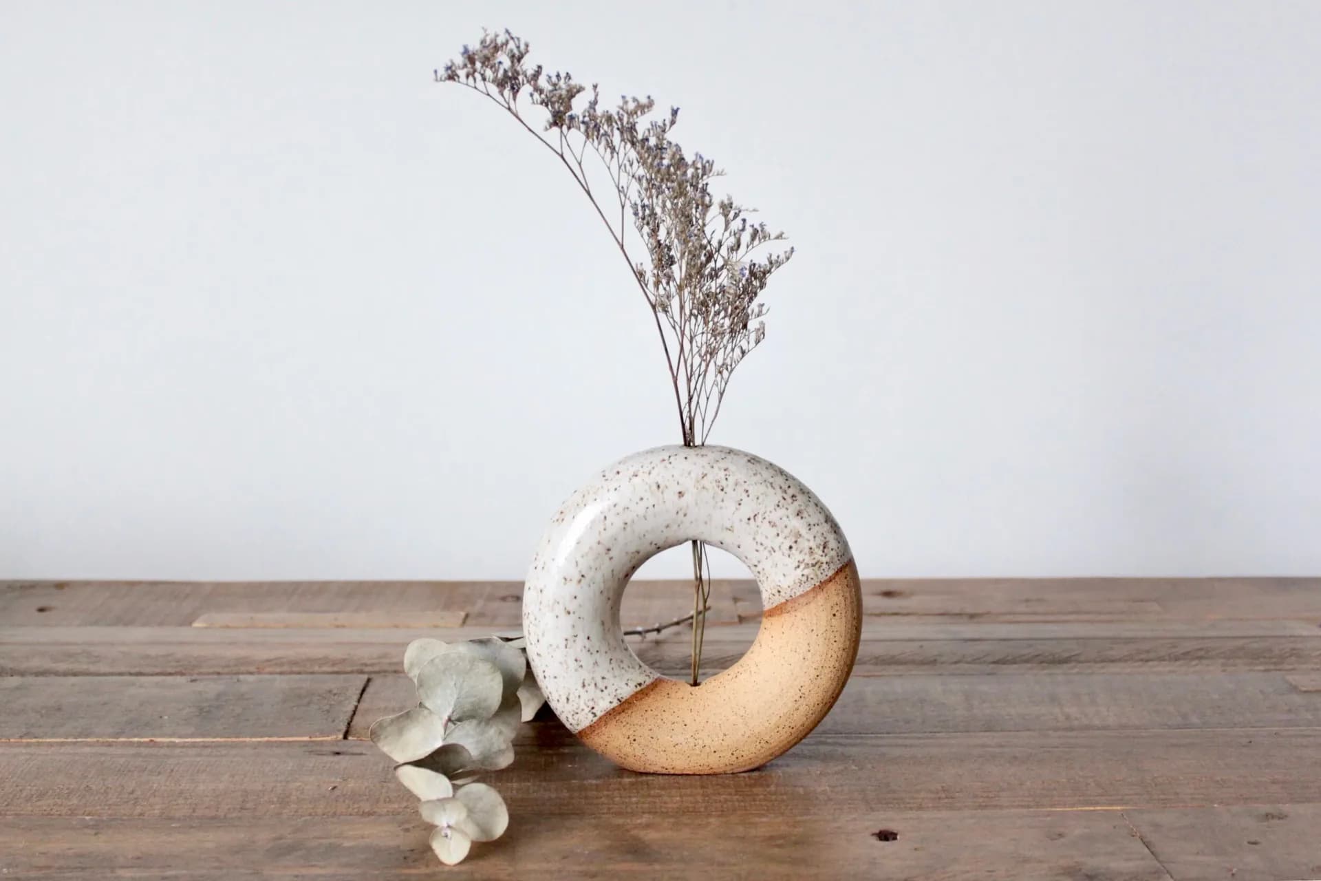 Speckled ring-form donut vase with half-glaze dip in natural stoneware, with dried flowers