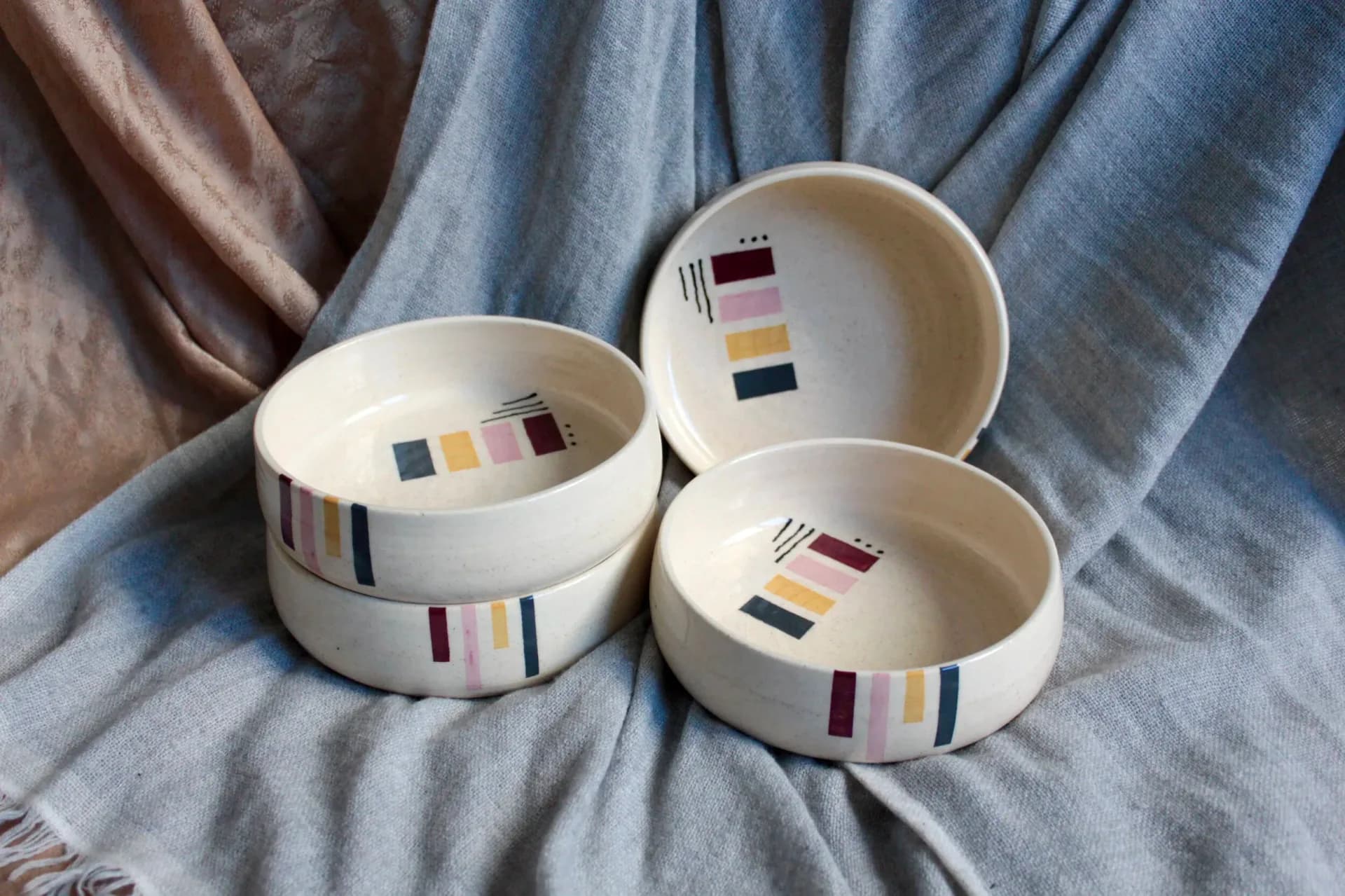 Three stacked stoneware bowls in white, cream, and brown speckled glazes