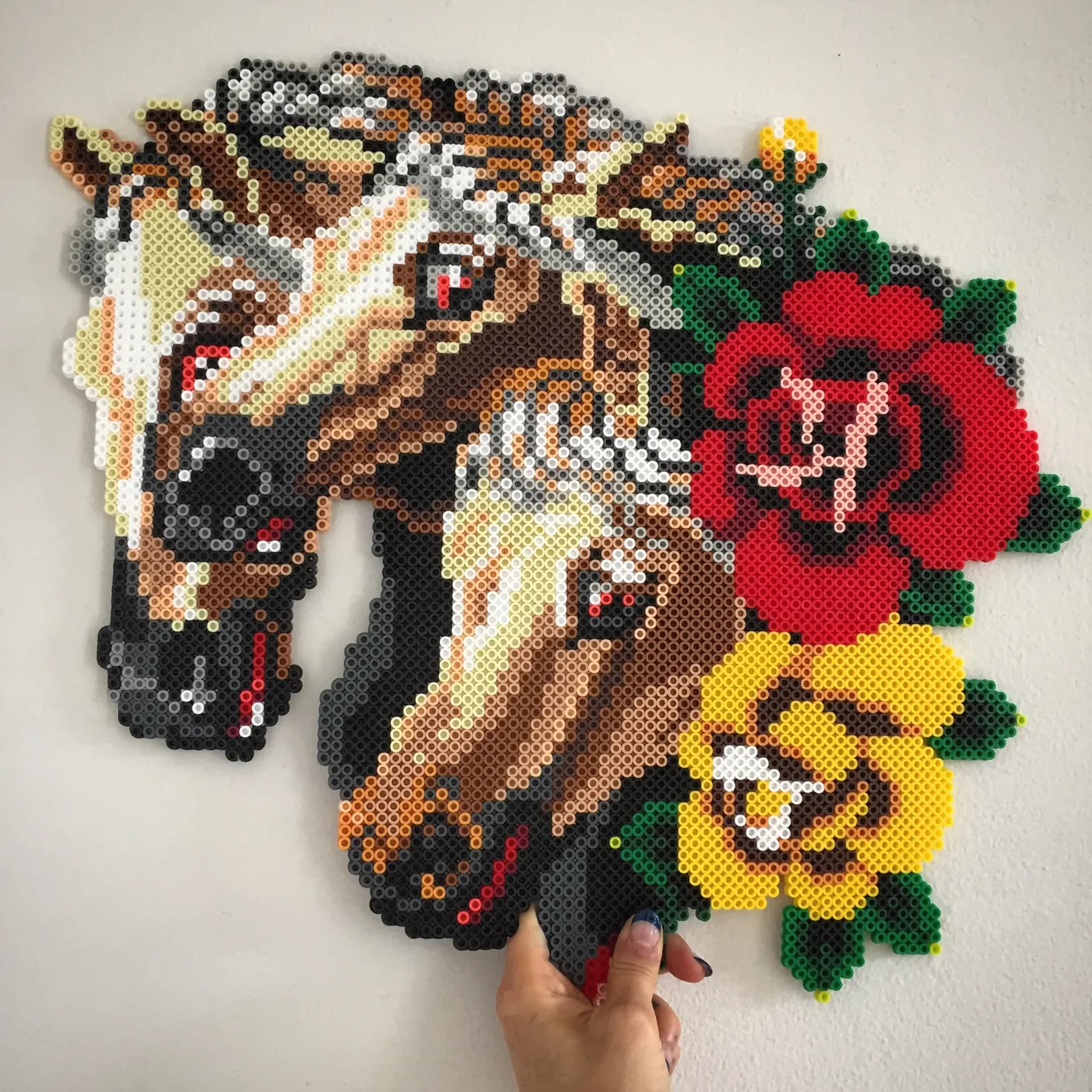 Large perler bead artwork of a horse head with red and yellow roses