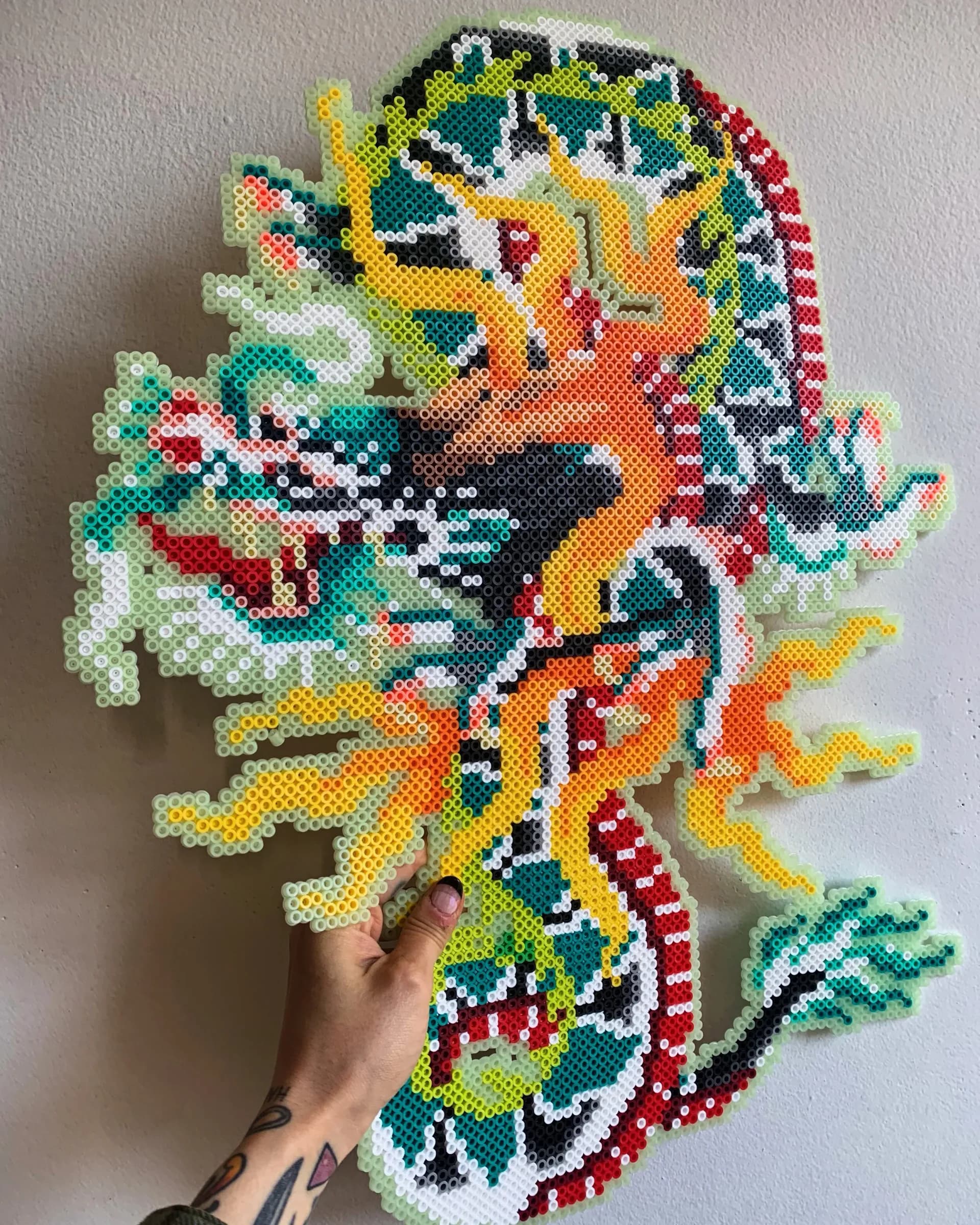 Large perler bead dragon artwork in teal, orange, and yellow
