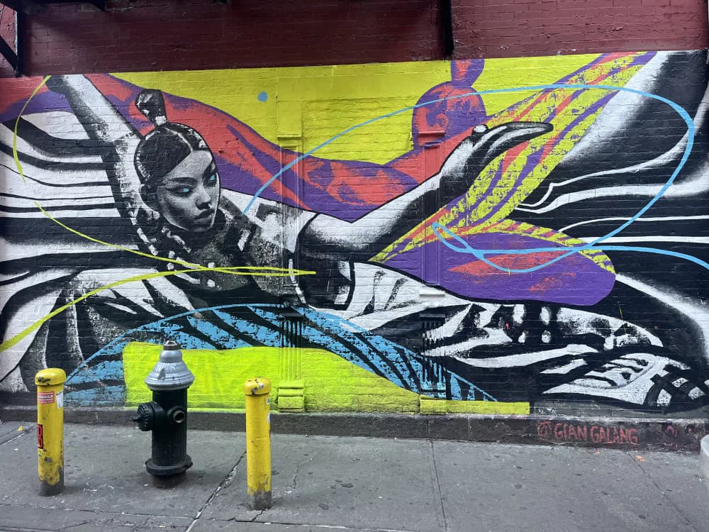 Close-up detail of Gian Galang's mural showing abstract figure with bold black and white linework layered over bright neon yellow background and dynamic colored forms.