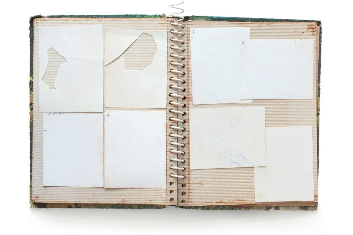Open spiral-bound sketchbook with aged pages showing tape, collage elements, and mixed sketches on white and textured paper.