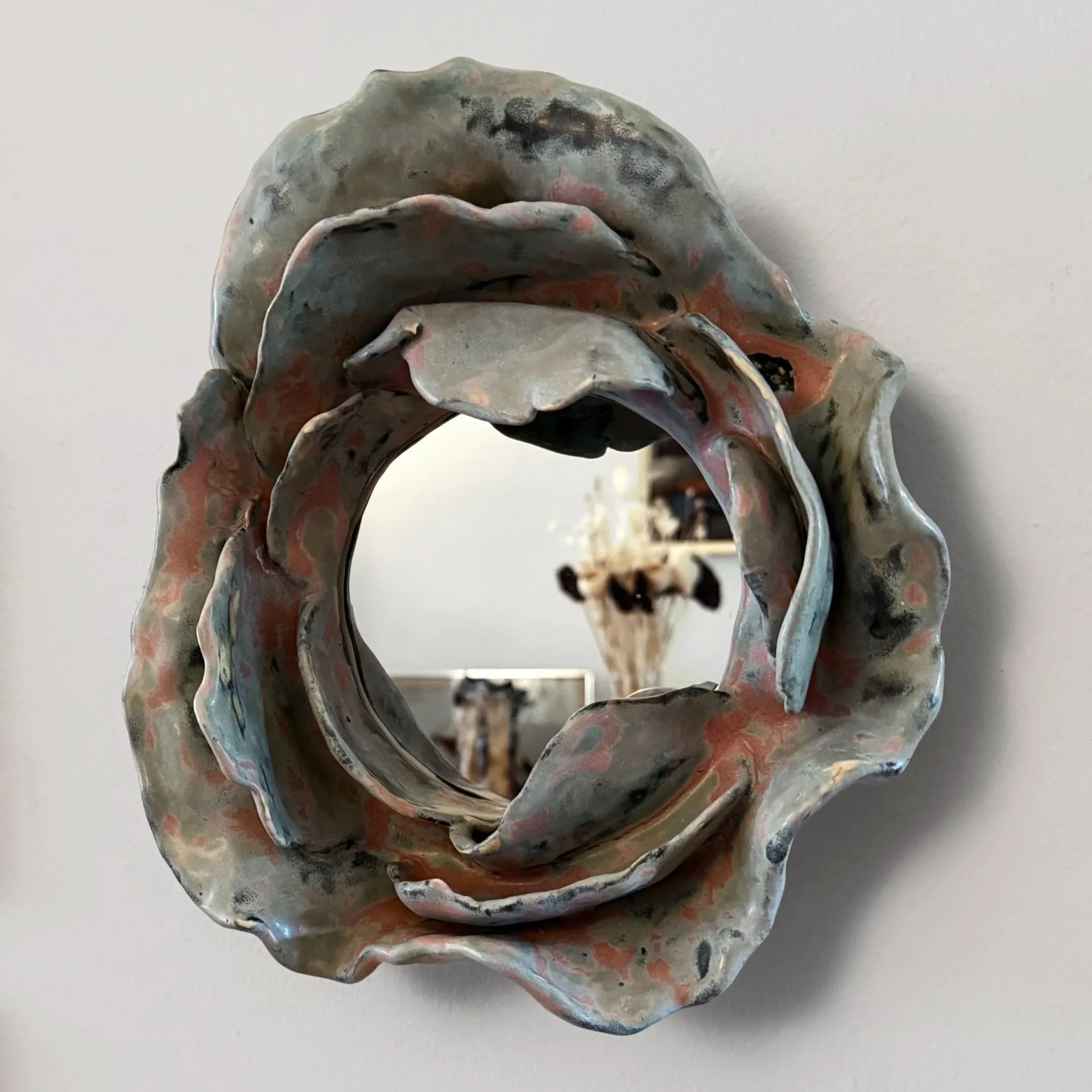 Ceramic wall sculpture mirror with rose-like organic form in grey and copper tones