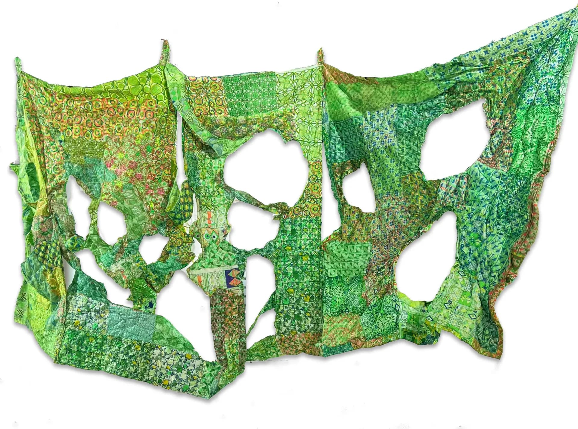 Large-scale green patchwork textile installation with cutout voids, hung on white wall