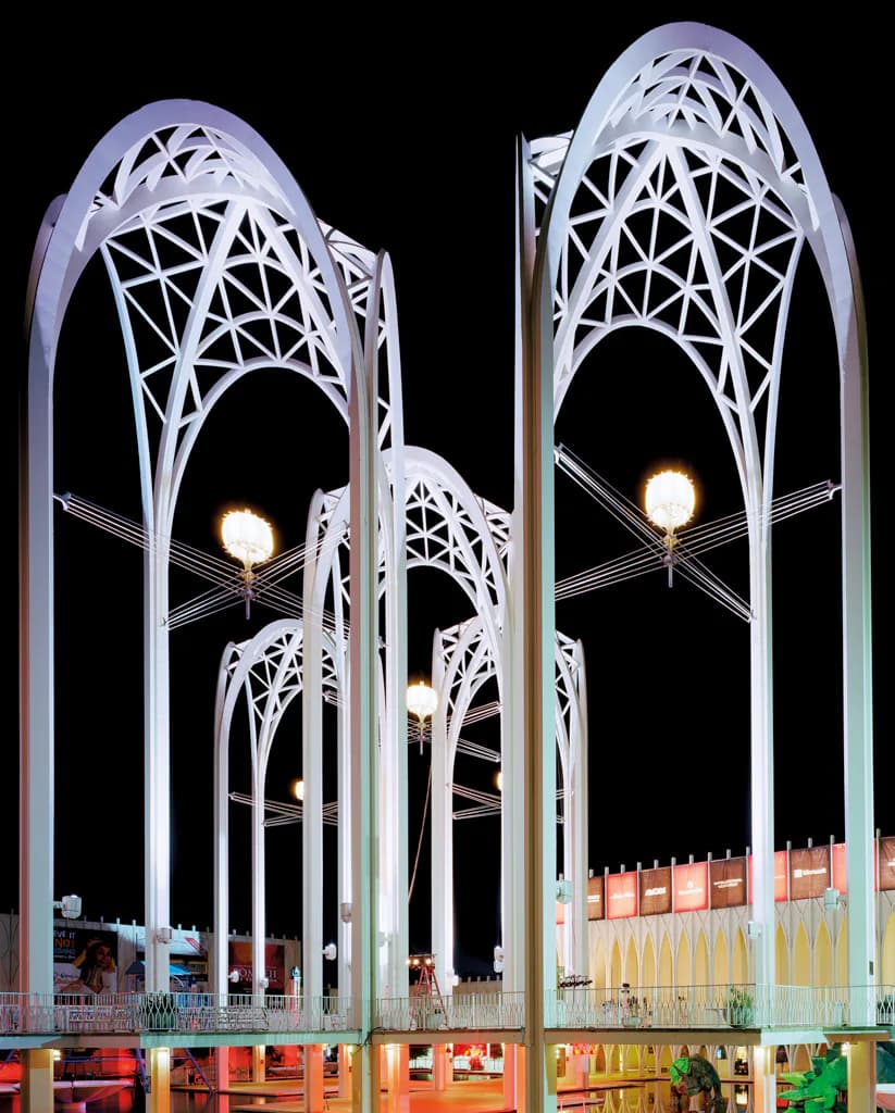 White latticed gothic arches of a World's Fair pavilion illuminated at night against black sky