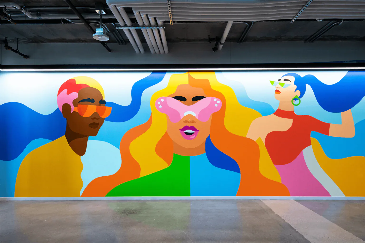 Large-scale mural featuring three stylized figures with colorful flowing hair and retro sunglasses on a blue background