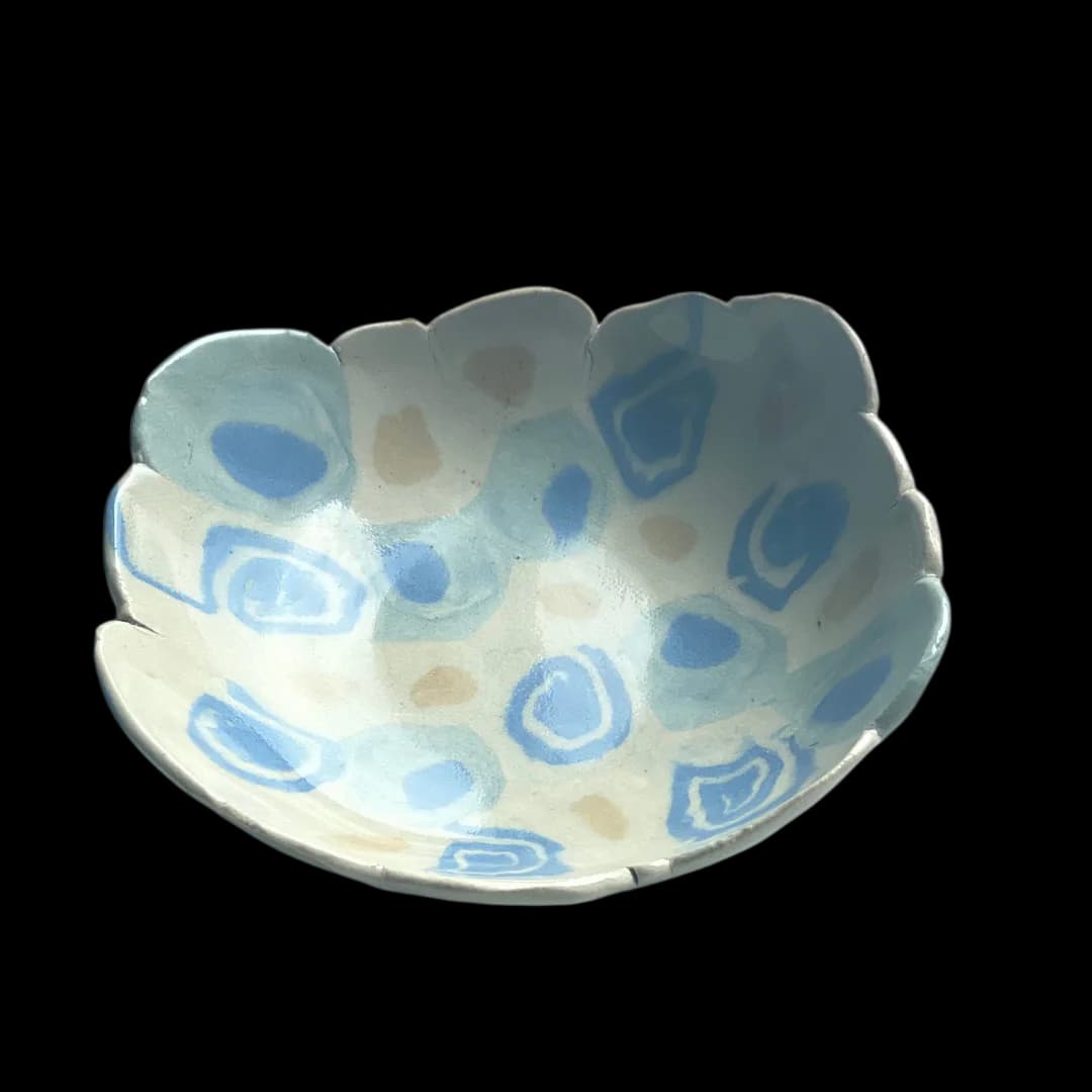 White ceramic bowl with scalloped rim and blue agate-like circular pattern throughout the interior