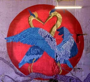 Mural of two blue herons forming a heart shape against a red circle