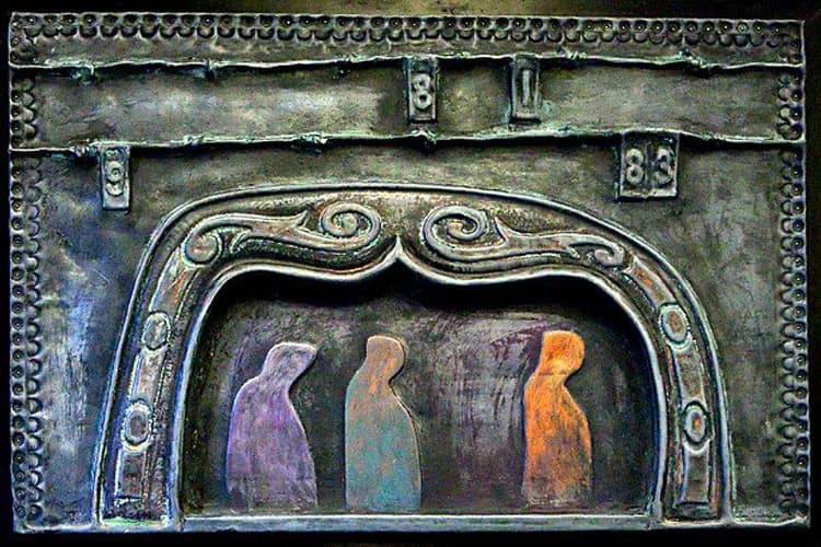 Bronze relief sculpture featuring three robed figures in purple, teal, and orange tones within an ornate arched frame with decorative scrollwork.