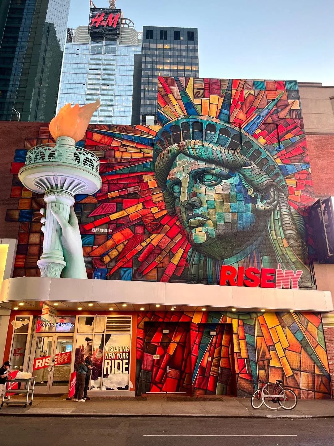 Massive Times Square building mural of Statue of Liberty face in mosaic stained-glass style with Rise NY signage