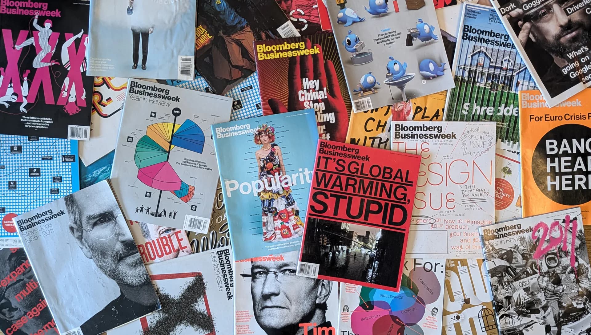 Collage of Bloomberg Businessweek magazine covers spread across a surface