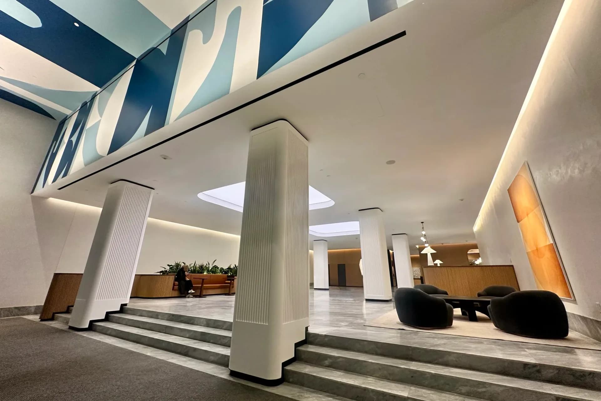 Large-scale blue and white abstract mural in a modern corporate lobby with decorative plaster walls