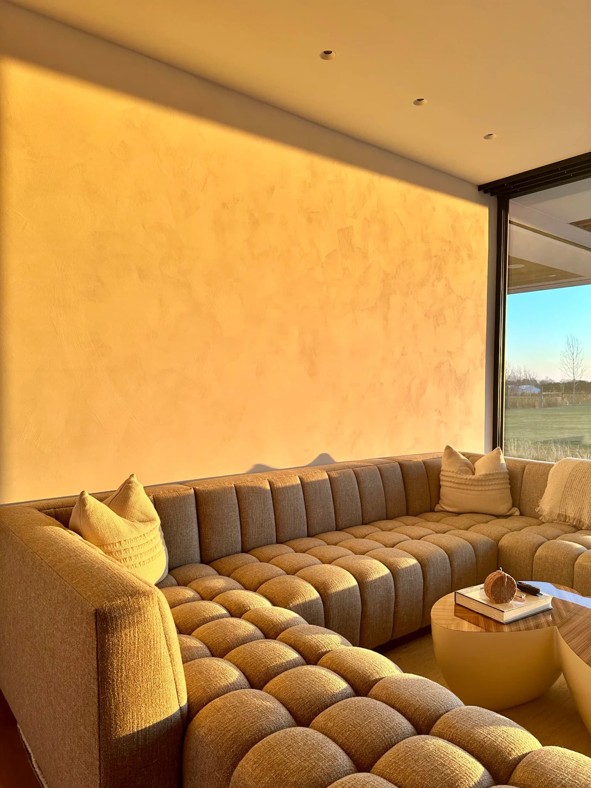 Warm golden venetian plaster wall glowing in afternoon sunlight in a modern living room