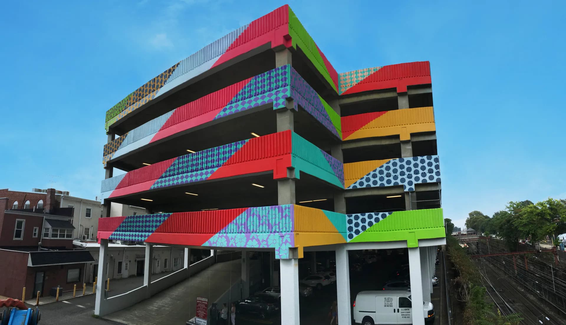 Colorful patterned mural on parking garage facade with bold geometric and pattern-filled bands