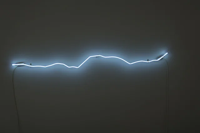 Minimalist neon light installation with an undulating cyan-blue line against a dark gray background, creating an atmospheric linear form.