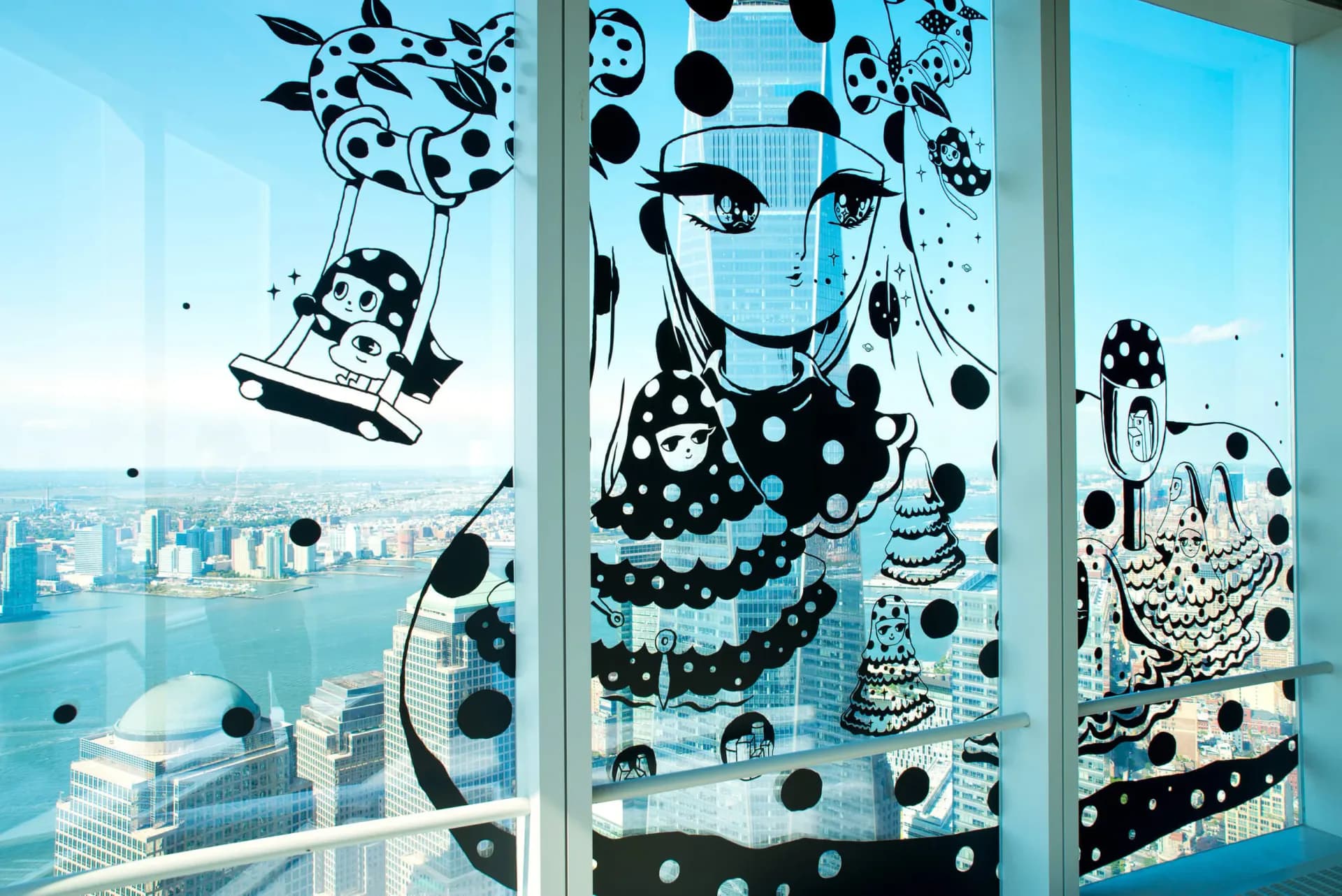 Large-scale black and white window installation featuring anime-style girl with polka dots overlooking New York City skyline