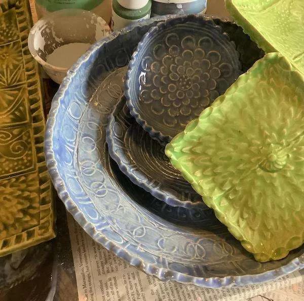 Collection of decorative ceramic bowls and plates with carved relief patterns and textures in black, white, and lime-green glazes.