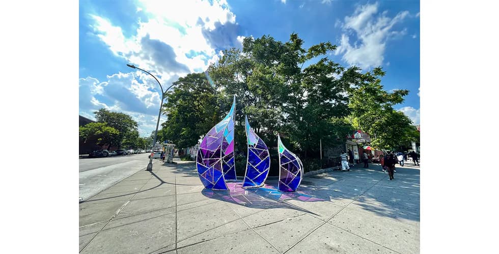 Large iridescent blue and purple teardrop-shaped outdoor sculptures on a city sidewalk