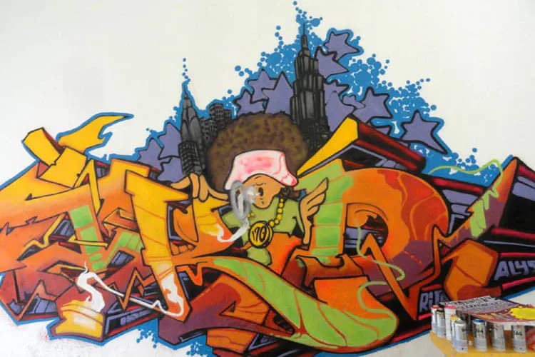 Colorful graffiti-style mixed-media artwork by Julius 'Terrible Tkid170' Cavero featuring dynamic yellow, orange, and red letter forms with blue star bursts and urban architecture elements in the background.