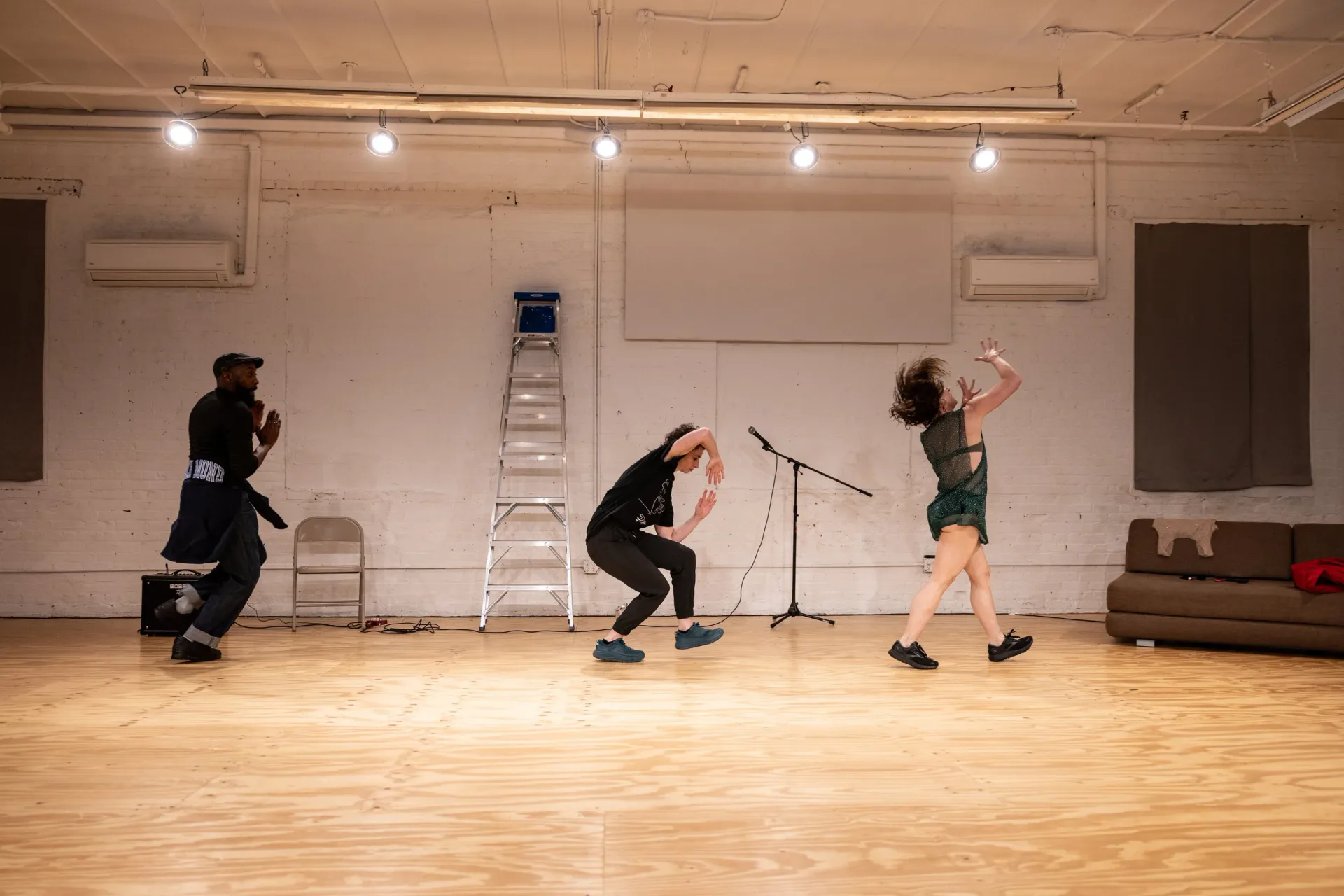 Group of performers in coveralls with structural scaffolding and colorful installation before audience