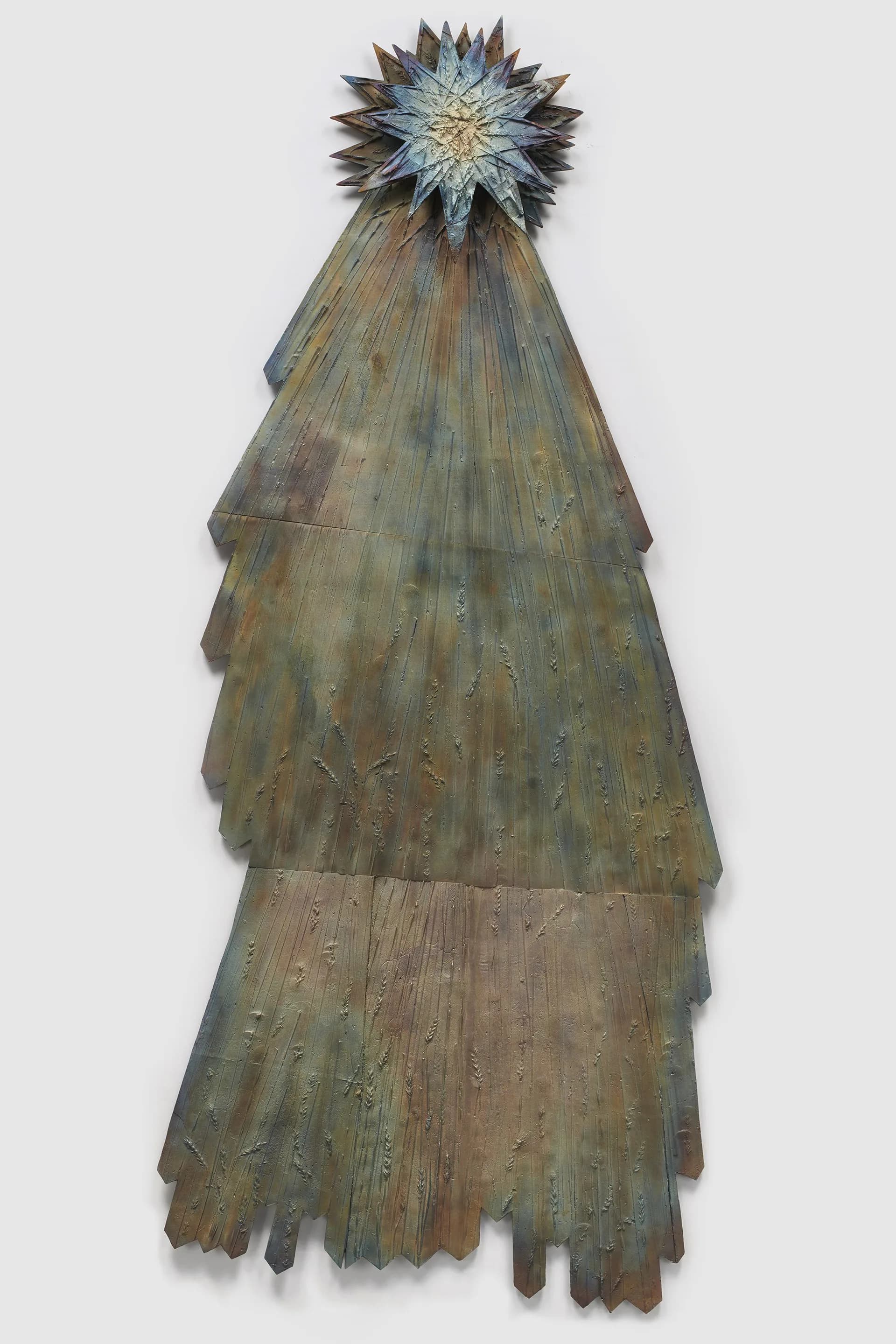 Tall conical sculpture made of layered weathered wood strips, topped with a blue and gold star-like ornament.