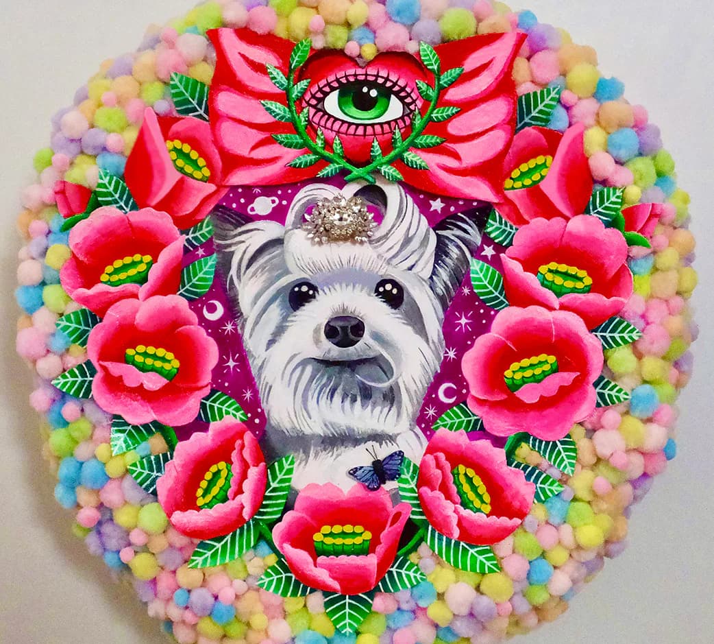 Circular mixed-media artwork featuring a dog portrait surrounded by painted roses and colorful pom-poms