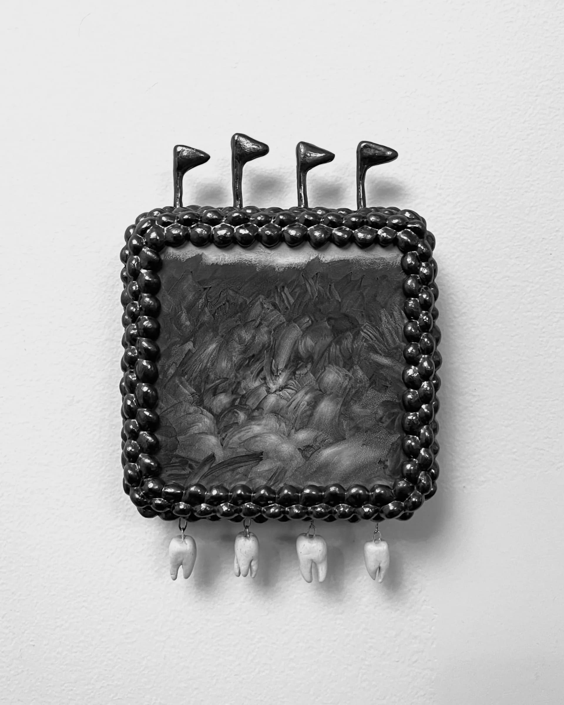 Square wall-mounted sculptural painting with flags on top, textured painted surface, and dangling ceramic tooth charms
