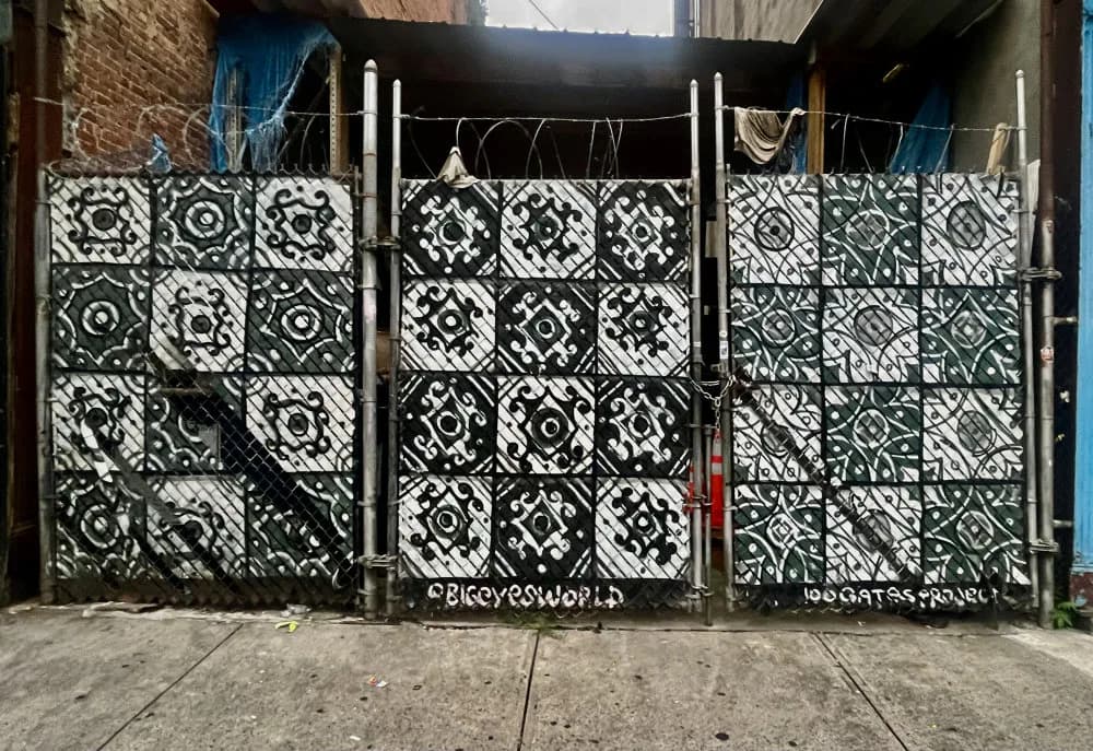 Black and white geometric mural on large gates depicting intricate mandala and circular patterns arranged in a grid composition.