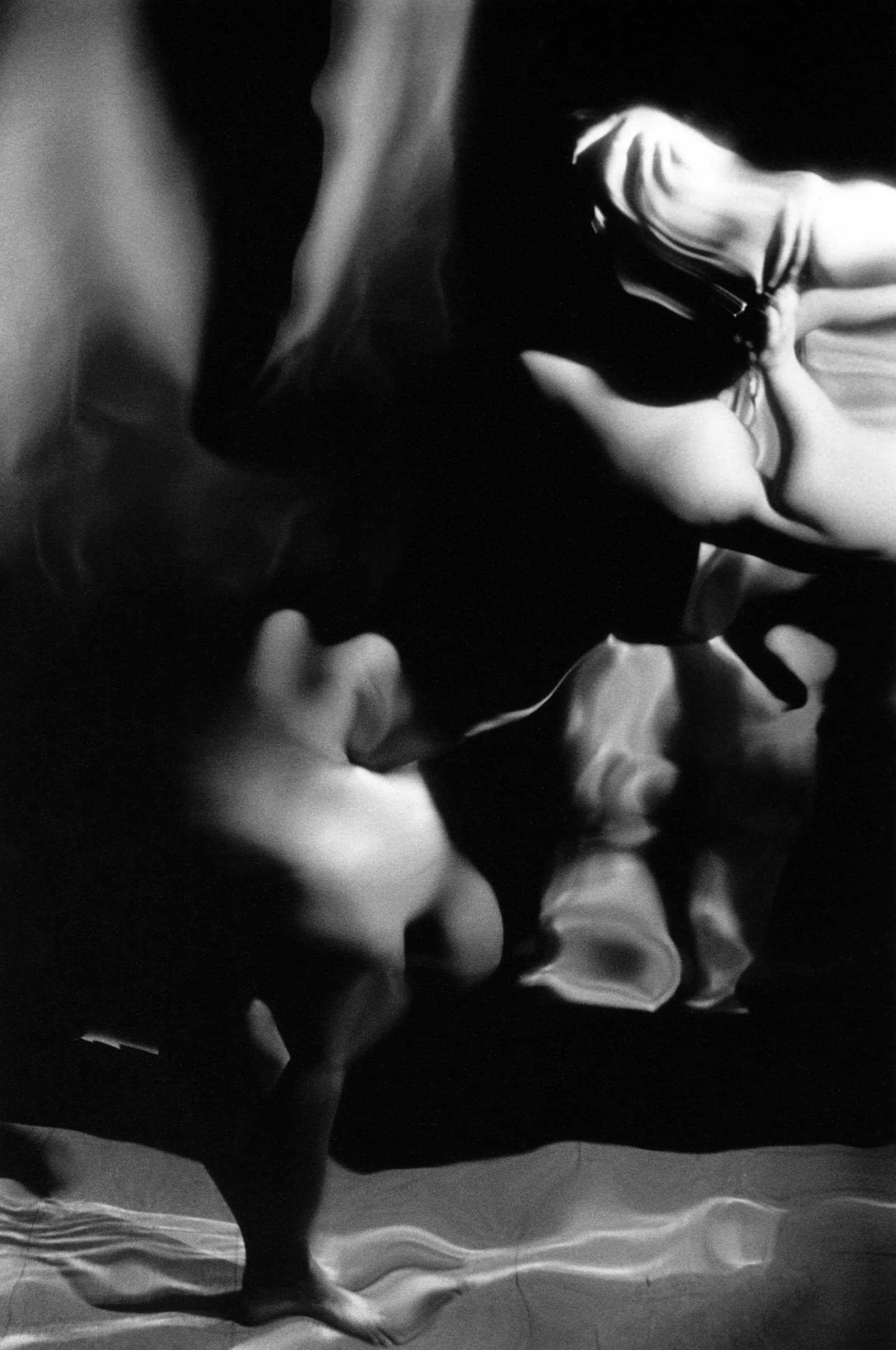 Black and white photograph of fragmented nude figures reflected in dramatic light