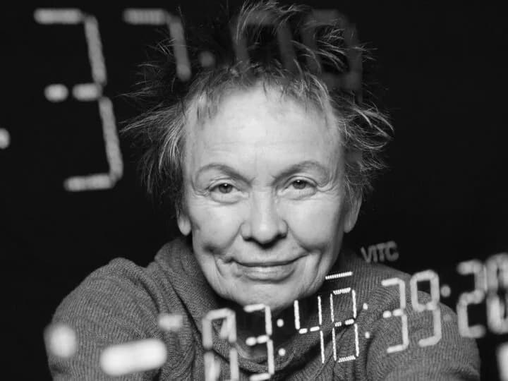 Black-and-white close-up portrait of a woman with tousled hair against a dark background with timecode visible.