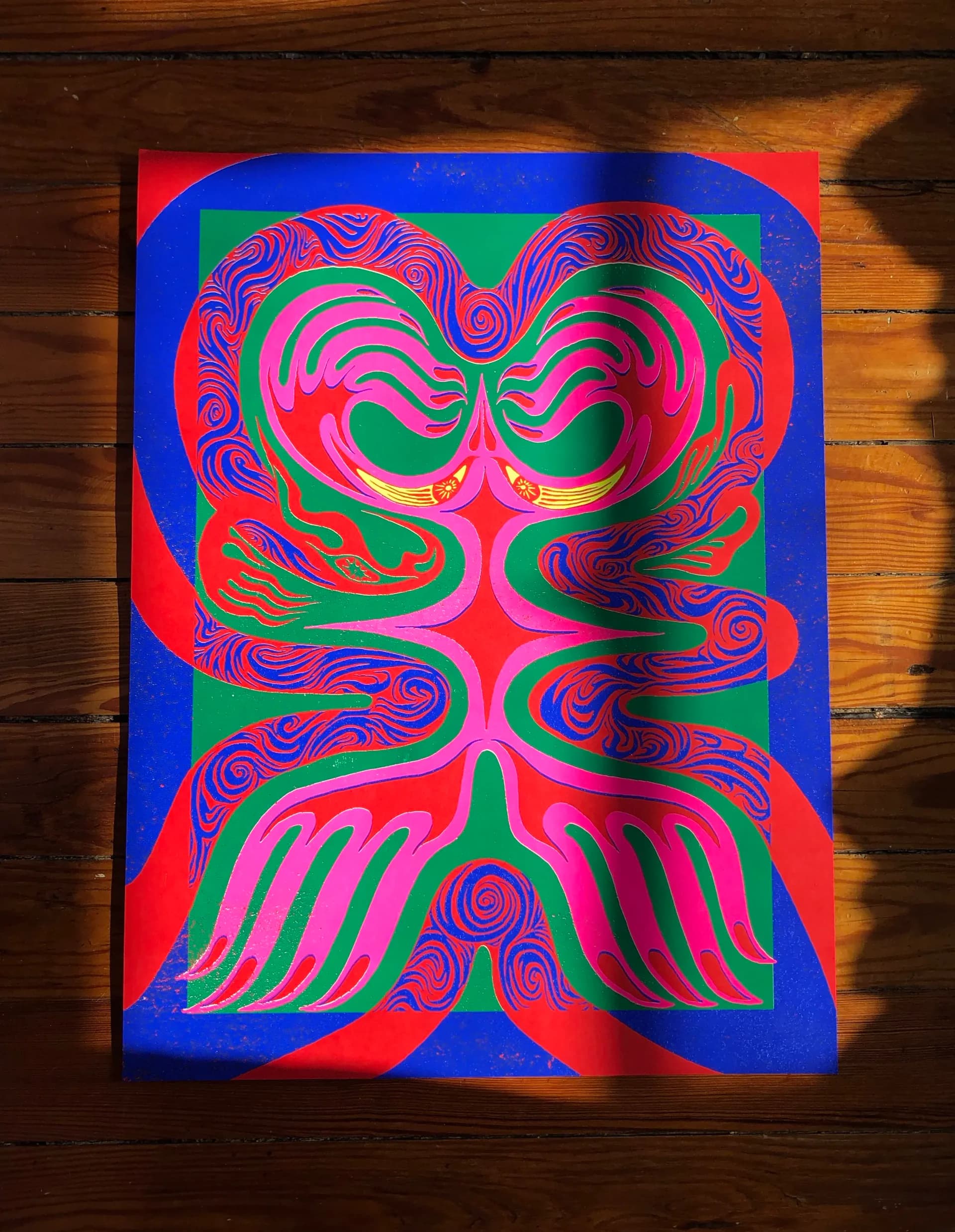 Psychedelic screenprint with mirrored creature figure in neon pink, blue, green and red on black paper