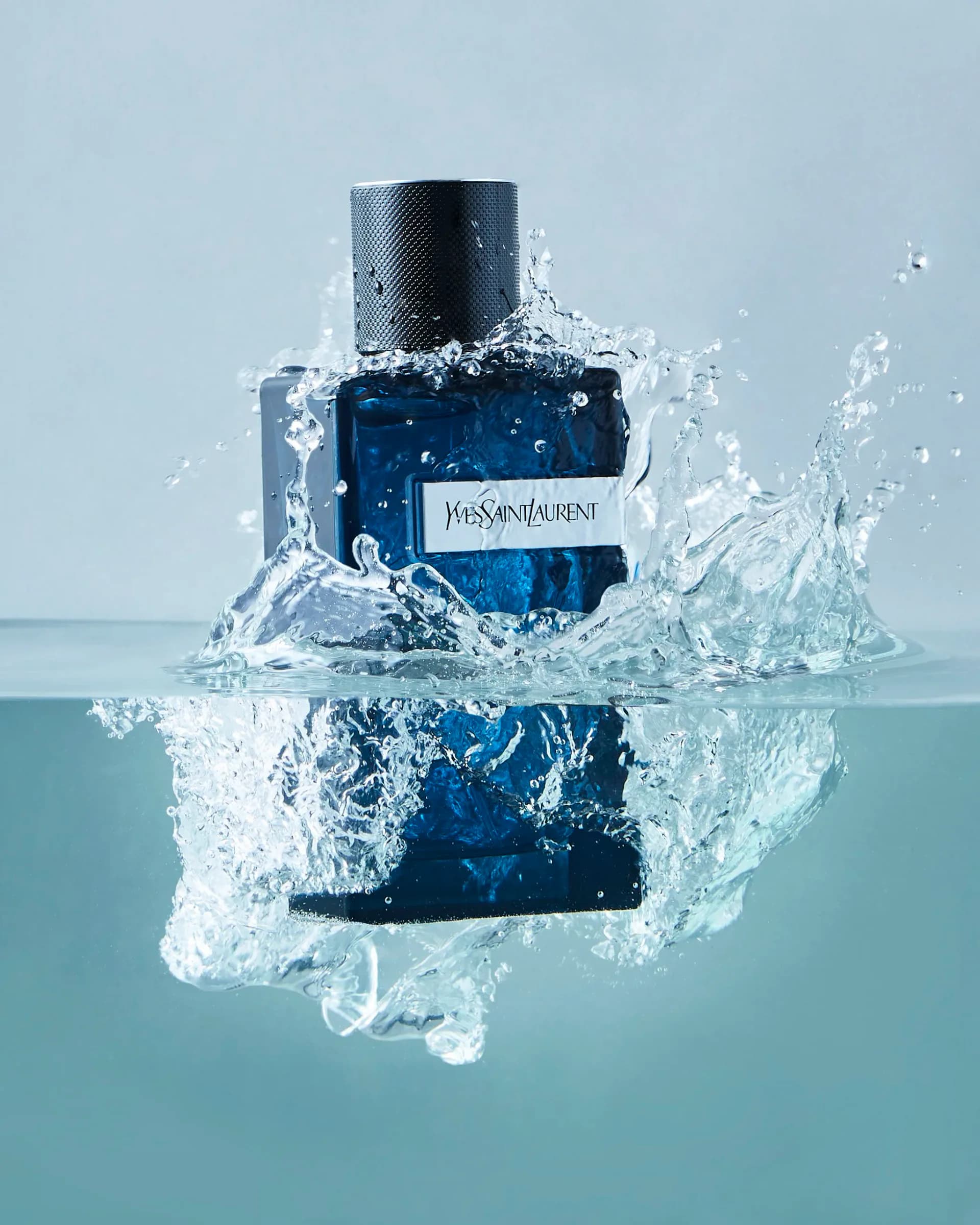 YSL blue fragrance bottle with dramatic water splash and reflection